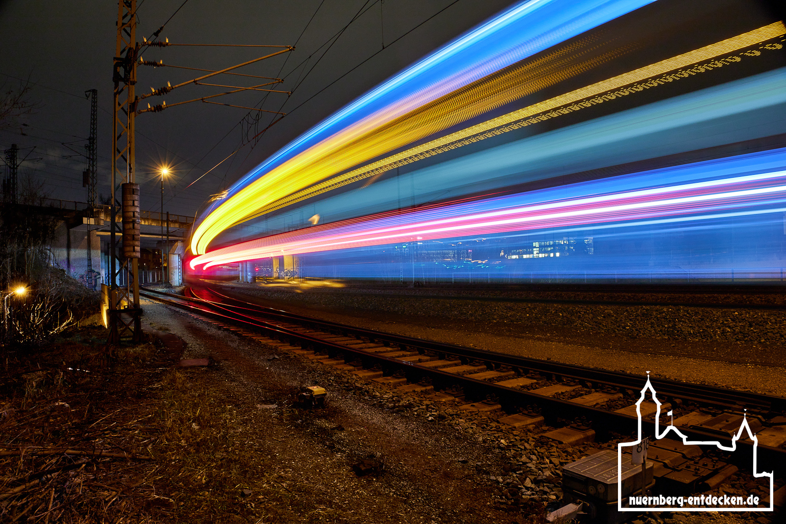 Zugdurchfahrt am Gleishammer in Nürnberg bei Nacht.