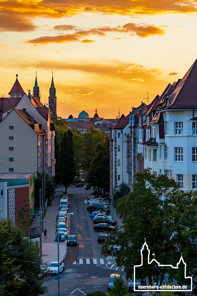 Blick entlang der Theodorstraße in Nürnberg während des Sonnenuntergangs, im Hintergrund die Türme der Lorenzkirche und die Kuppel der Elisabethkriche. - Foto: Ardan Füßmann