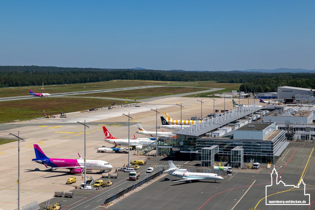 Das Terminalgebäude und Vorfeld des Albrecht-Dürer-Flughafens Nürnberg, vom Tower aus gesehen, zeigt Flugzeuge verschiedener Airlines an den Gates geparkt.